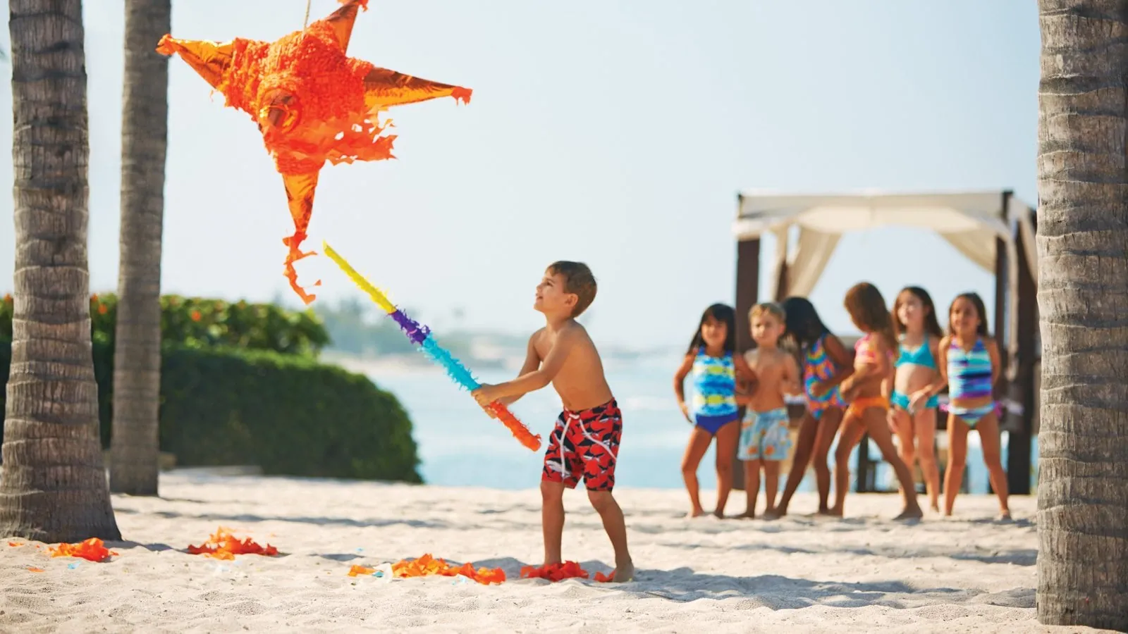 Children taking turns at a pinata on a Punta Mita beach during a family reunion