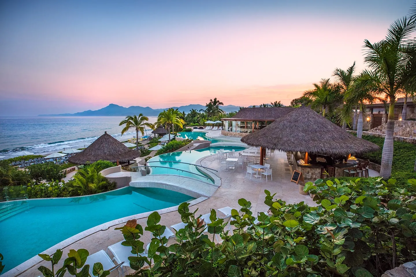 Kupuri Beach Club's pools and palapas at dusk in Punta Mita, a beach-club day out for the whole group
