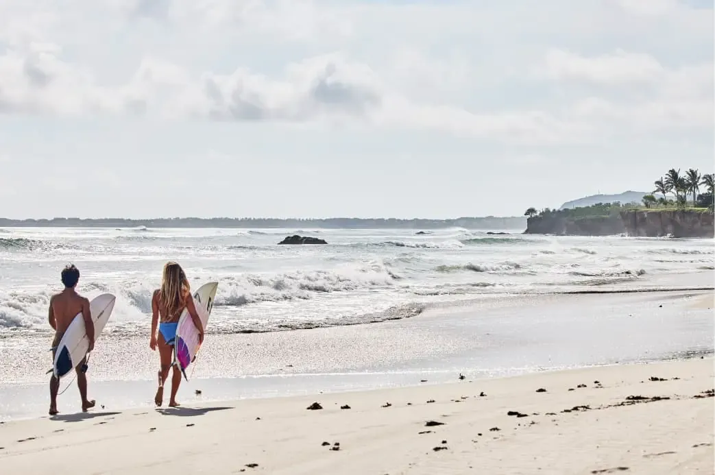 Two surfers walking a Punta Mita beach toward the waves, a surf session for the group