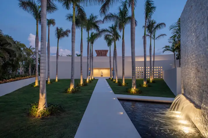 The palm avenue arrival at Casa Akai, lit at dusk