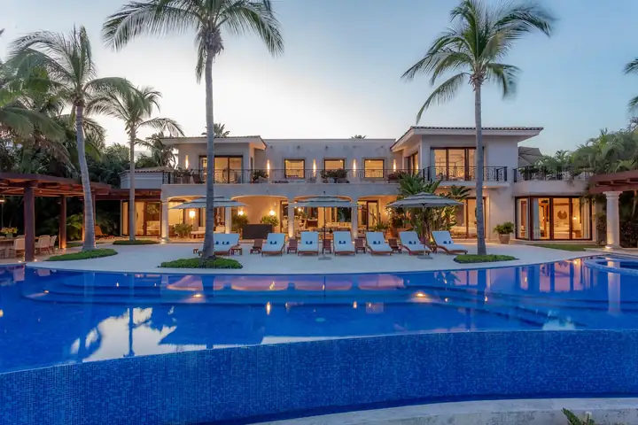 Casa La Vida lit at dusk, the second of the two group villas, its pool glowing in front