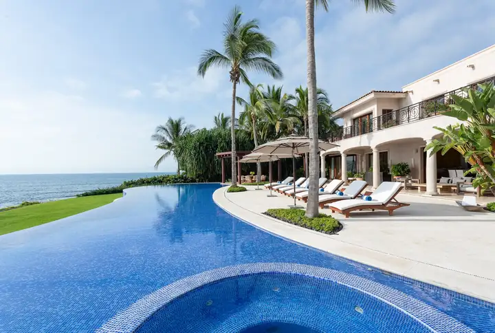 The infinity pool and lawn at Casa La Vida, the bay on the horizon